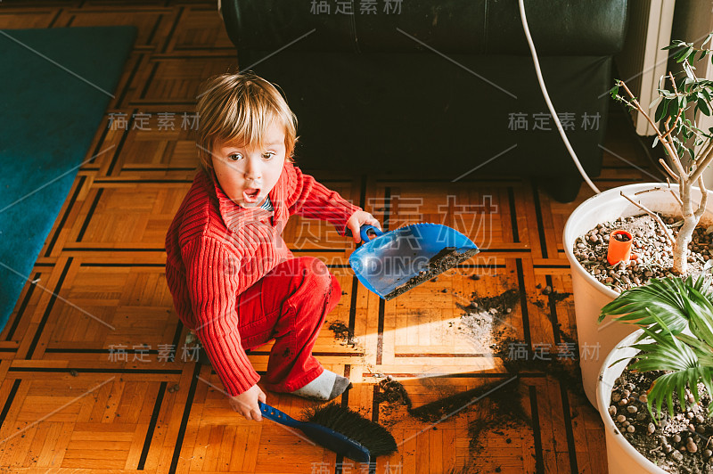 非常脏乱的婴儿，面部表情滑稽，正在清理地板上的植物土壤