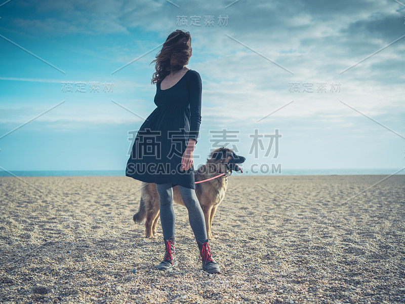 一个年轻女人和一只大狗在海滩上