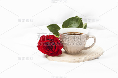 白床单上放着红玫瑰的黑咖啡