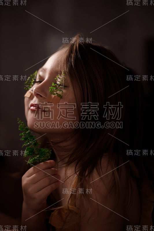 生态学概念，孩子的肖像与蕨类植物的小枝贴在她的脸颊上，拿着小枝