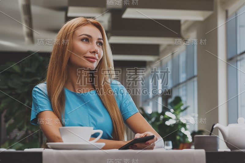 漂亮的红发女人在咖啡厅享受早餐