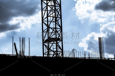 黑暗多云的天空下是建筑工地起重机的剪影