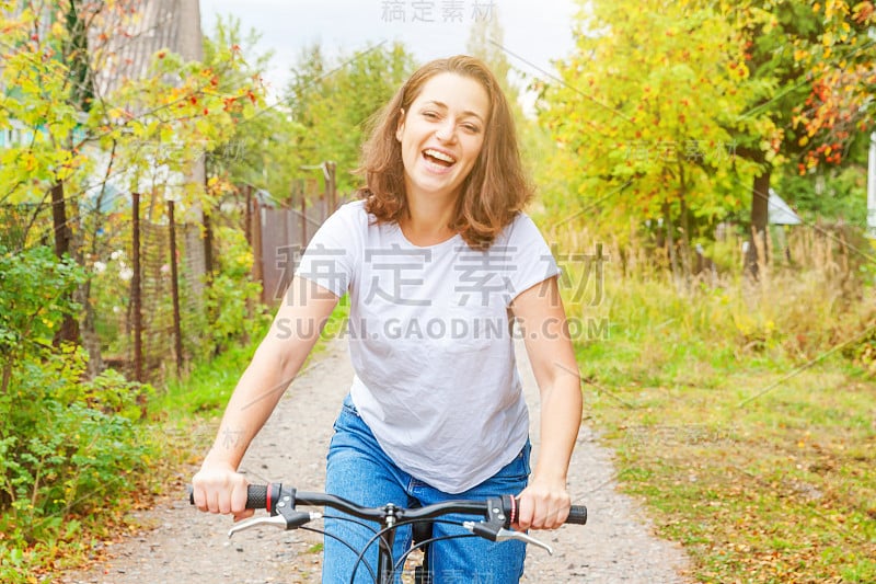 年轻女子骑自行车在夏季城市公园户外。活跃的人。嬉皮士女孩放松和骑自行车。在夏天骑自行车去上班。自行车