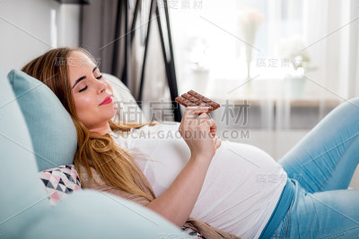 孕妇微笑着在家享受着吃巧克力