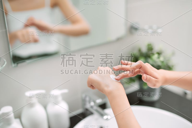 身体保健的概念。沐浴后在手上和指甲上涂抹保湿护手霜的女性。