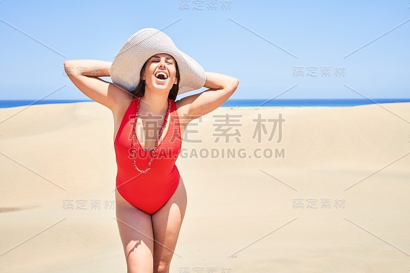 年轻美丽的女人日光浴穿着夏季swinsuit在马斯帕洛马斯沙丘bech