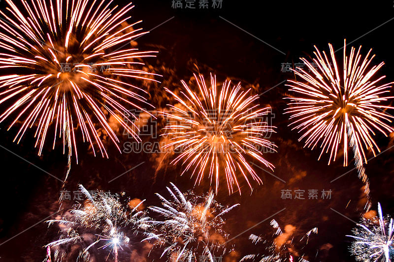 各种五颜六色的烟花在夜空的背景。用黄色和橙色的闪光致敬。