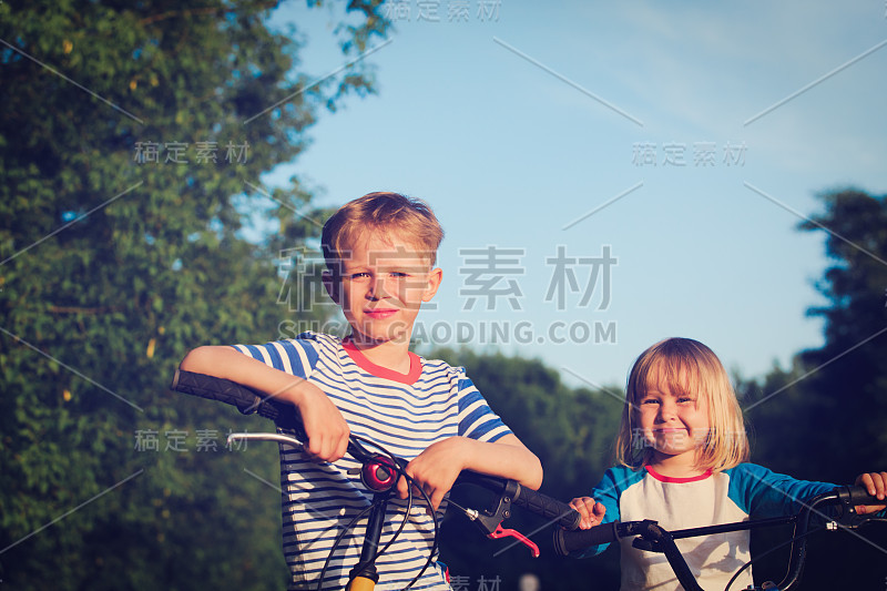 快乐的小男孩和小女孩在大自然中骑自行车