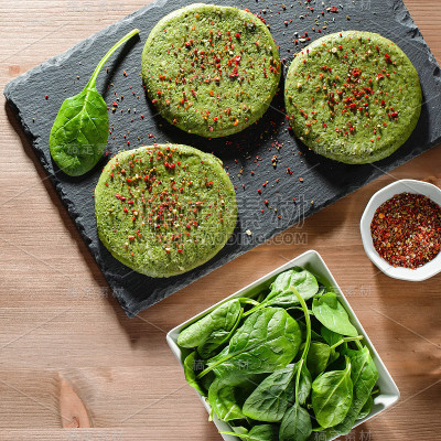 在强光下，石盘上放着生的绿色鸡肉和香料菠菜汉堡，俯视图。饮食健康理念，晚餐节食理念，减肥友好食品，乡