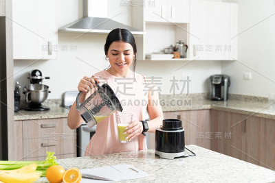快乐的白人妇女享受果汁在厨房