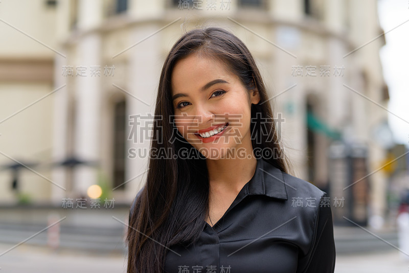 美丽的亚洲女商人肖像在城市街道的户外微笑，而看起来自信