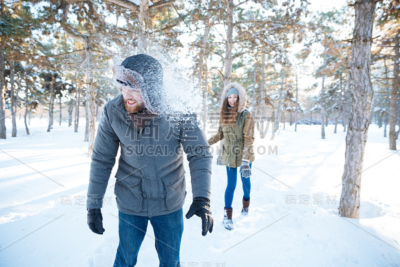 快乐的女人扔雪球在英俊的男人