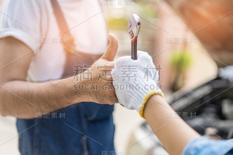 机械师在车库里检查和修理一辆坏了的汽车。机修工的手和工具