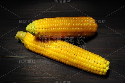 黑色背景上的煮熟的玉米棒子。