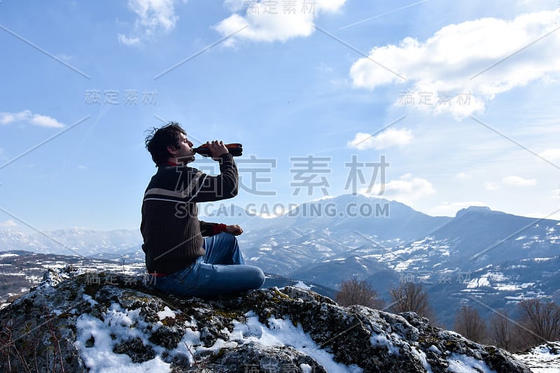 一名游客在山顶上喝着啤酒，感受着自由