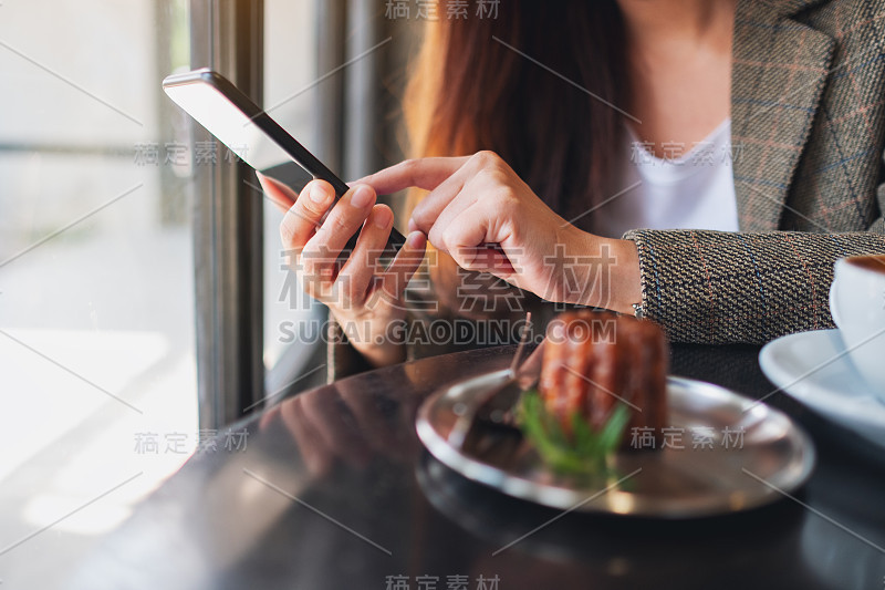 一个女人拿着手机，在咖啡馆的桌上放着咖啡杯和零食