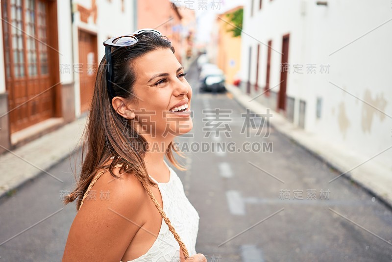 在一个阳光明媚的夏天，年轻美丽的女人快乐地走在城市的街道上