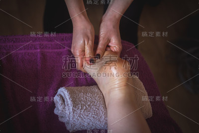 理疗师在水疗中心给一位女士做脚底按摩