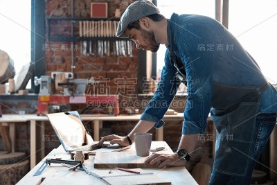 成功英俊的商人与时髦的帽子工作在木工