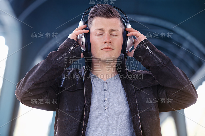 一个戴着耳机的年轻人站在街上
