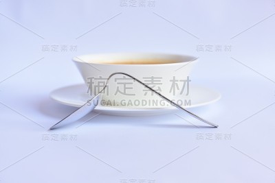 白色汤碗旁边倾斜的金属勺子，缺乏功能