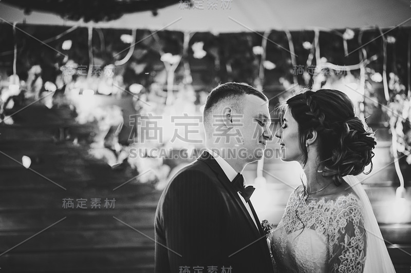 结婚誓言。木墙背景上的新娘和新郎接吻。新婚夫妇站在拱门下举行夜礼。黑白照片。